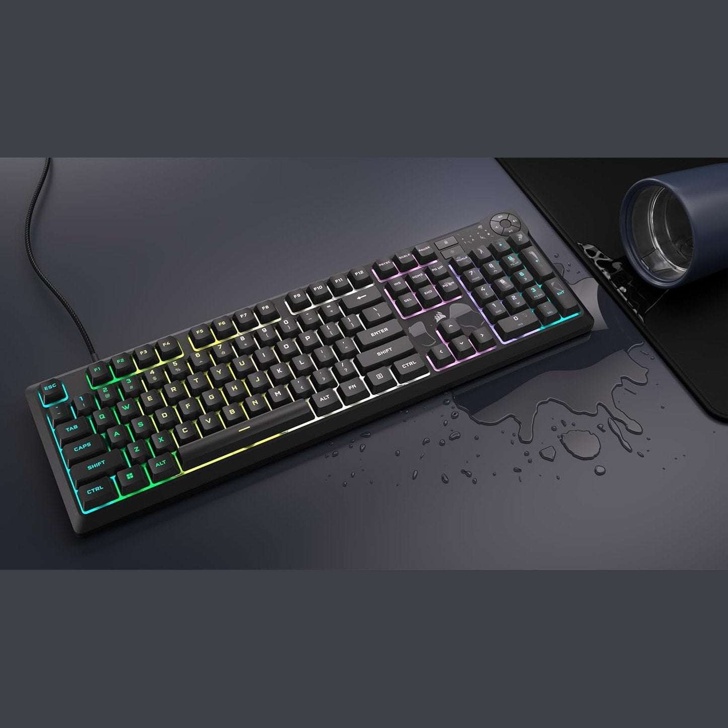 Black Corsair K55 CORE RGB keyboard with rainbow backlit keys, water droplets on surface